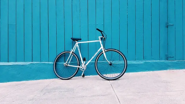 Bici da città bianca appoggiata a una parete azzurra